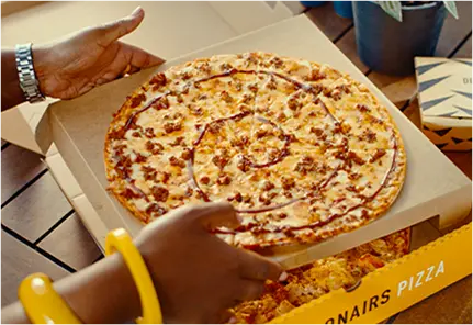 Person removing a takeaway pizza from a pizza box
