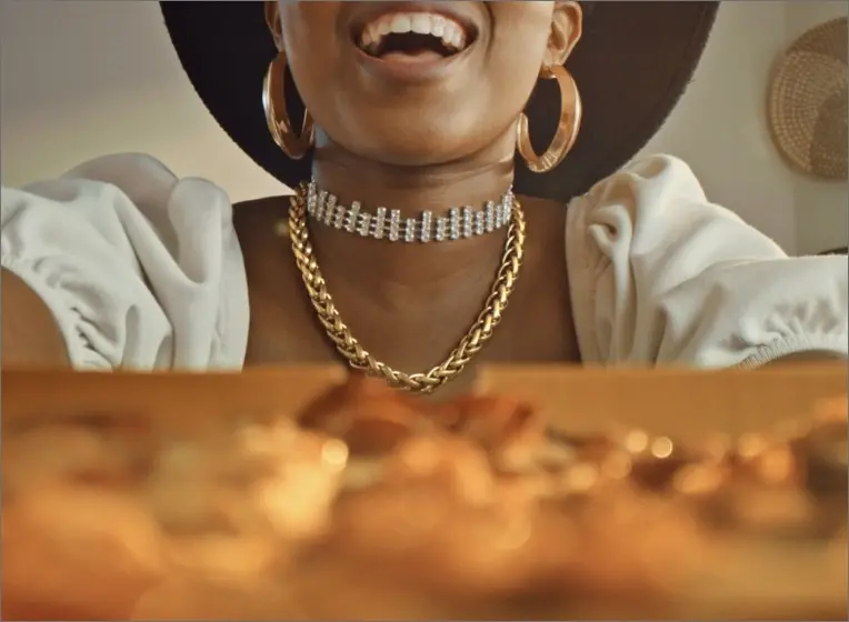 Lady wearing bold jewellery reaching for pizza
