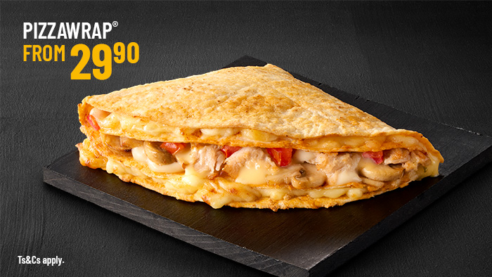 A golden-brown pizza wrap, folded and filled with melted cheese, tender chicken, mushrooms, and diced tomatoes on a dark slate.